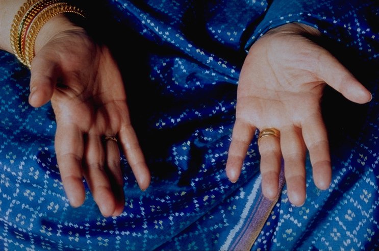 Open palms during Sahaja Yoga meditation, against blue fabric.